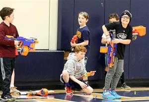 kids playing nerf in a gym